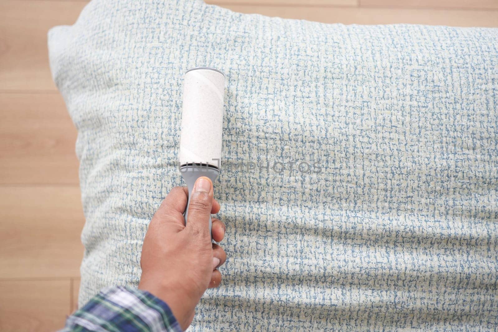 using an adhesive roller to remove lint and fluff from a bed