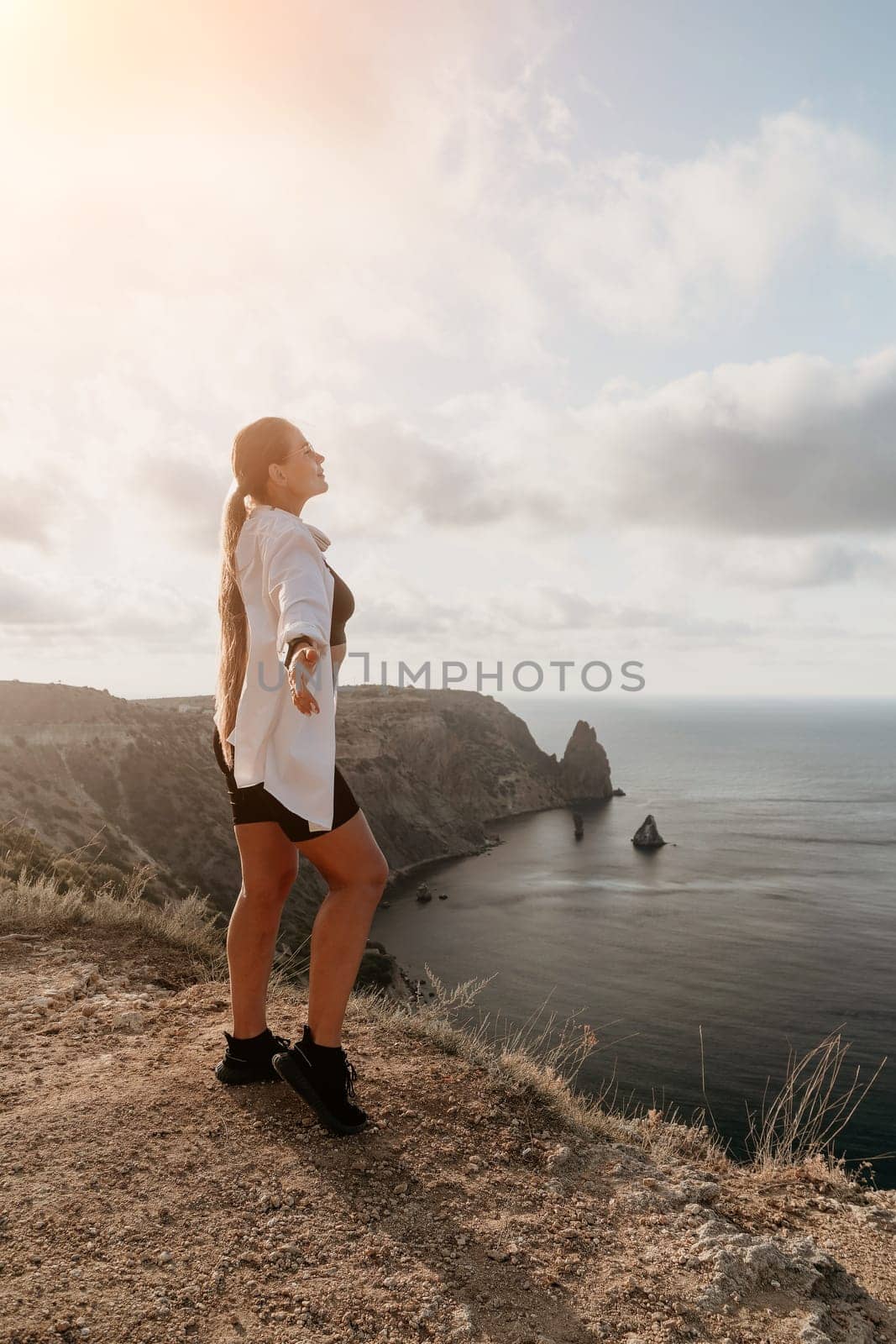 Woman travel sea. Young Happy woman in a long red dress posing on a beach near the sea on background of volcanic rocks, like in Iceland, sharing travel adventure journey