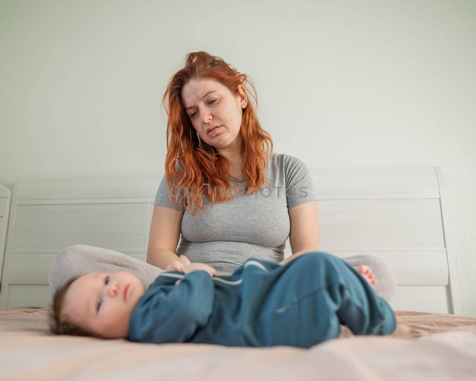 Woman with postpartum depression sitting on bed next to newborn