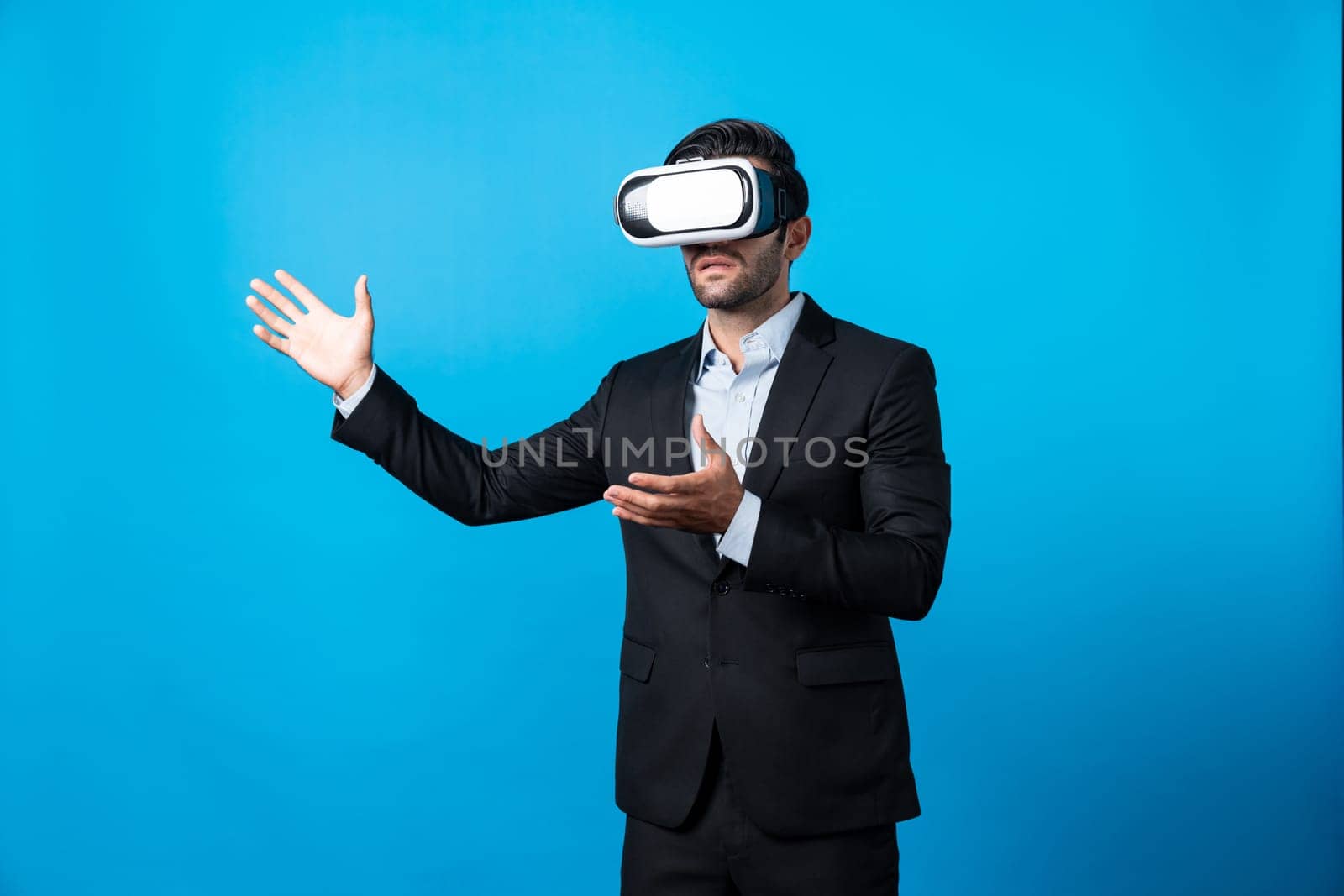 Business man looking data analysis by using VR glasses. Project manager checking business strategy by enter in metaverse or virtual reality world while wearing suit at blue background. Deviation.