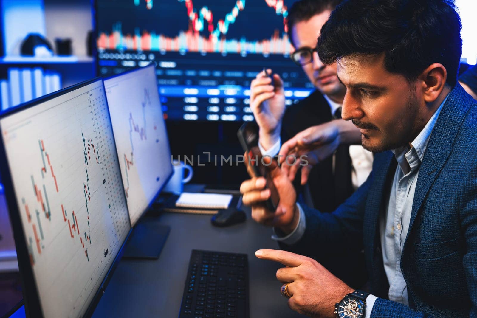 Two stock exchange traders researching data on smartphone and laptop screen server of dynamic digital currency. Investors analyzing market stock at decorative neon blue-light of workplace. Sellable.