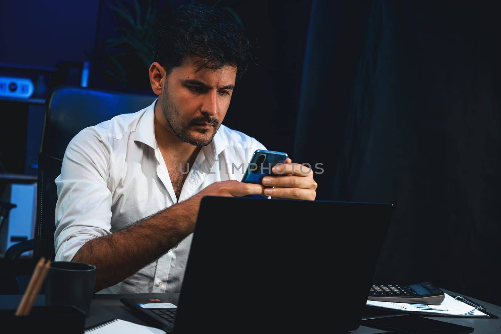 Working businessman using smartphone with customer or coworker to send email at neon workplace, searching data information on phone at remotely online working space in over time at night. Sellable.