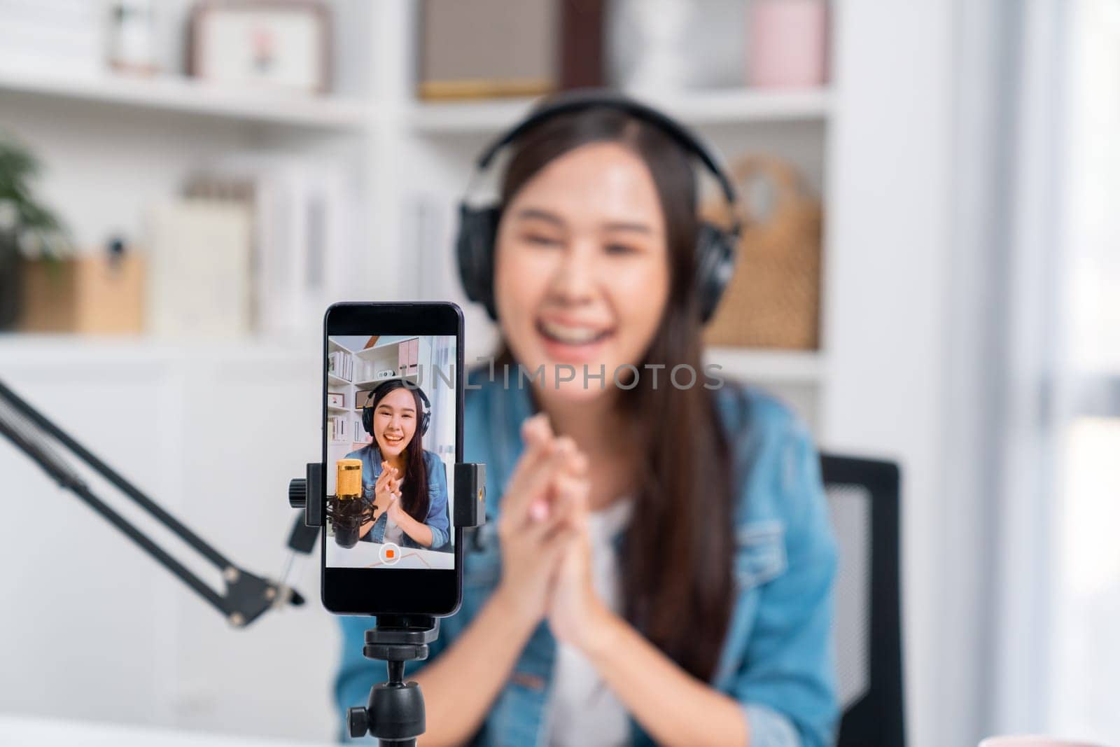 Selective focus phone in host channel of young beautiful Asian in creative broadcaster talking online explaining to promote marketing or consultant in daily life with listener at studio. Stratagem.