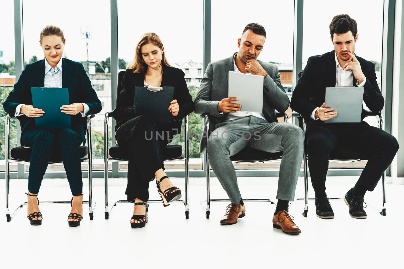 Businesswomen and businessmen holding resume CV folder while waiting on chairs in office for job interview. Corporate business and human resources concept. uds