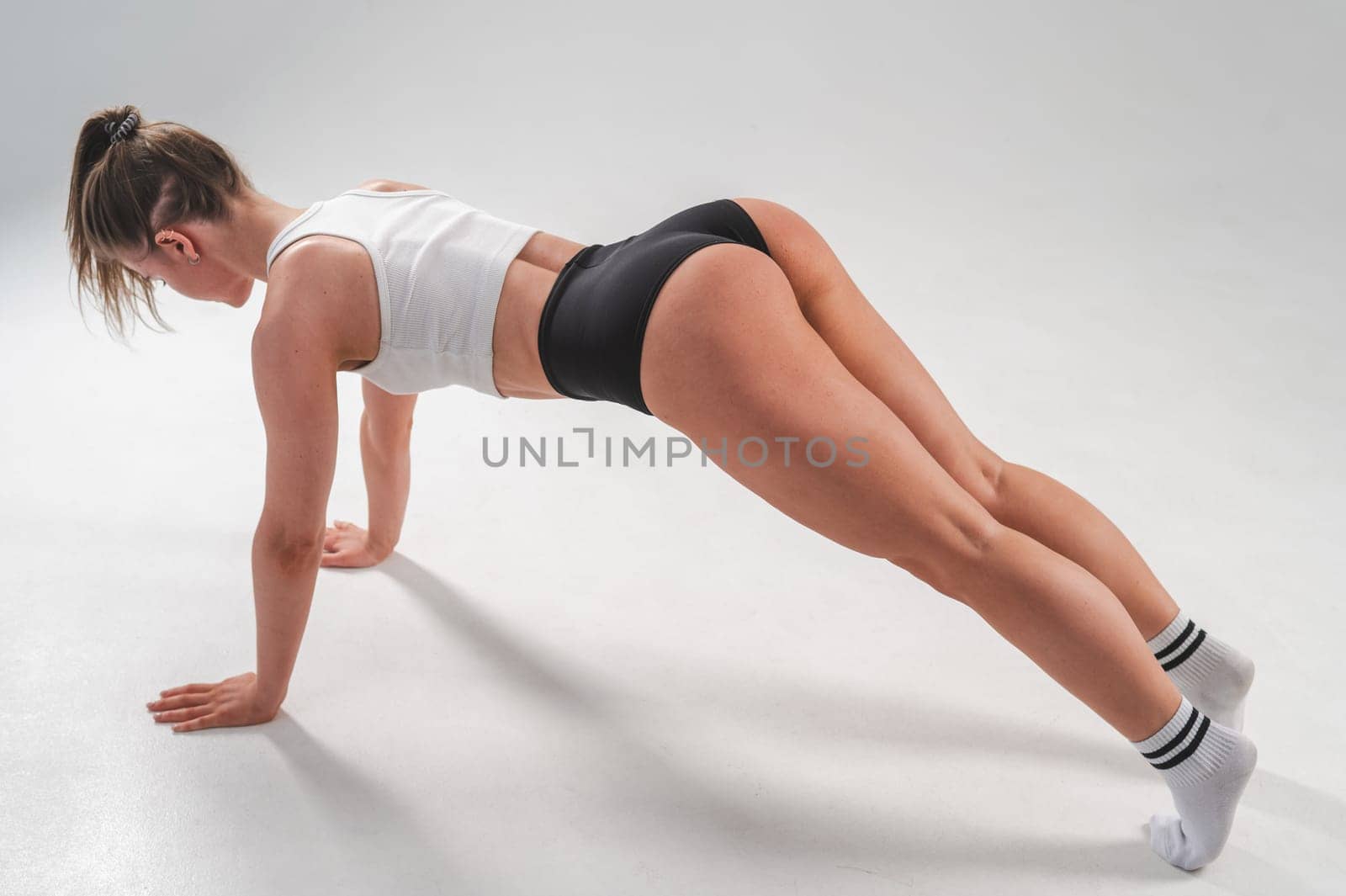 Athletic woman in shorts doing plank on white background. by mrwed54