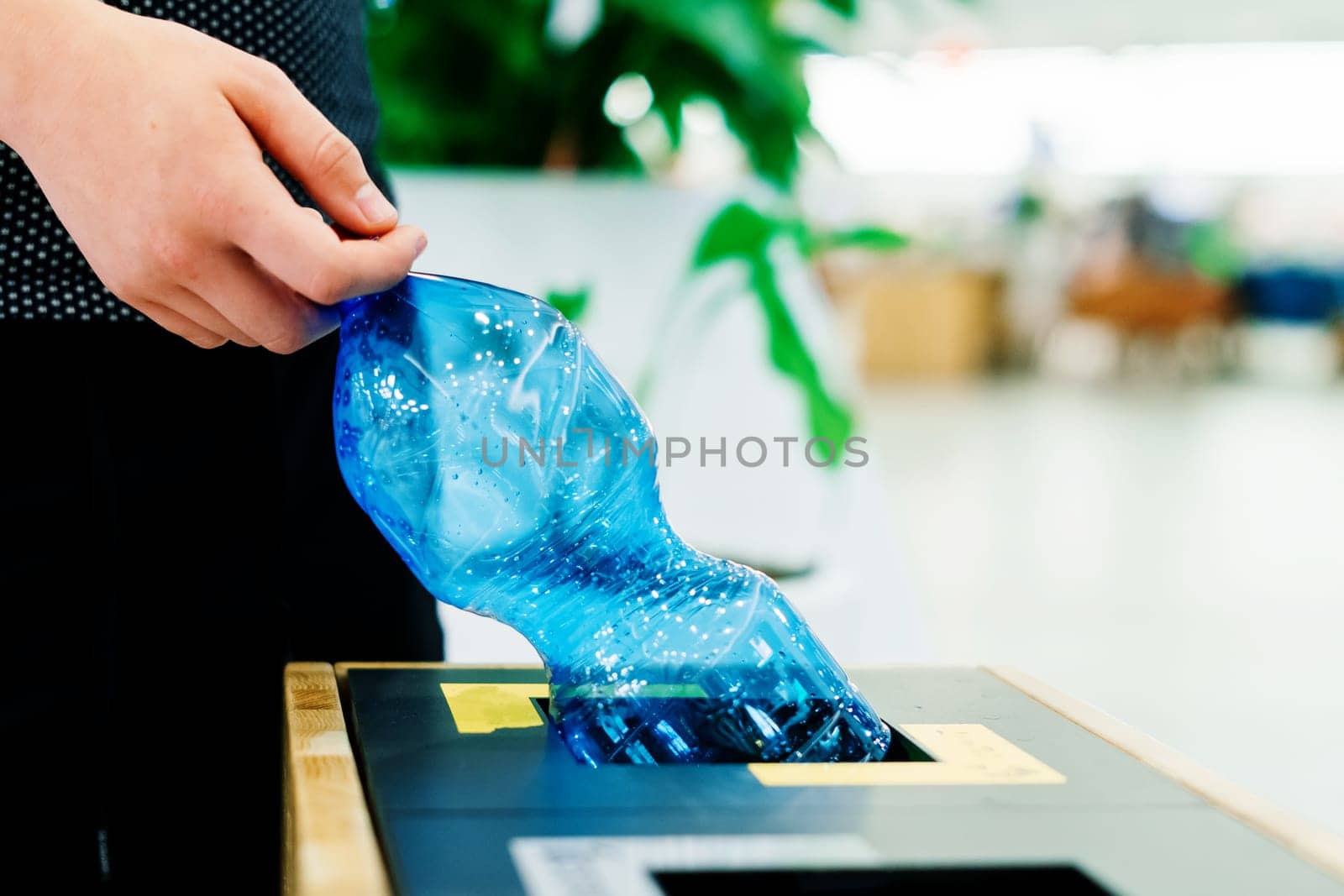 Hand of young man throwing plastic bottle in a recycling trash bin