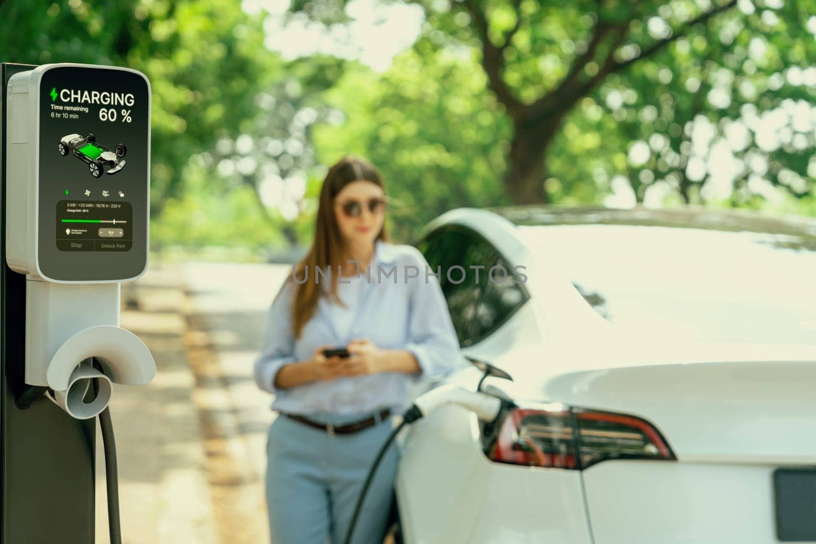 Young woman using smartphone to pay for electric car charging. Exalt by biancoblue