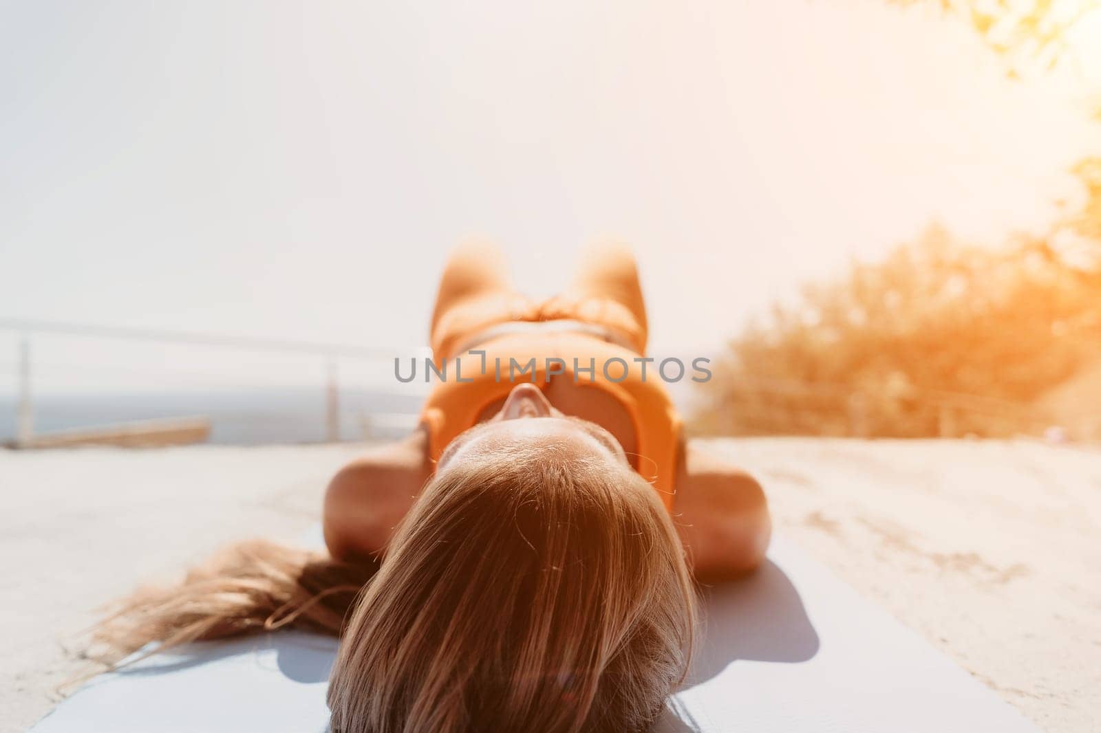 Fitness woman sea. Outdoor workout on yoga mat in park near to ocean beach. Female fitness pilates yoga routine concept. Healthy lifestyle. Happy fit woman exercising with rubber band in park.