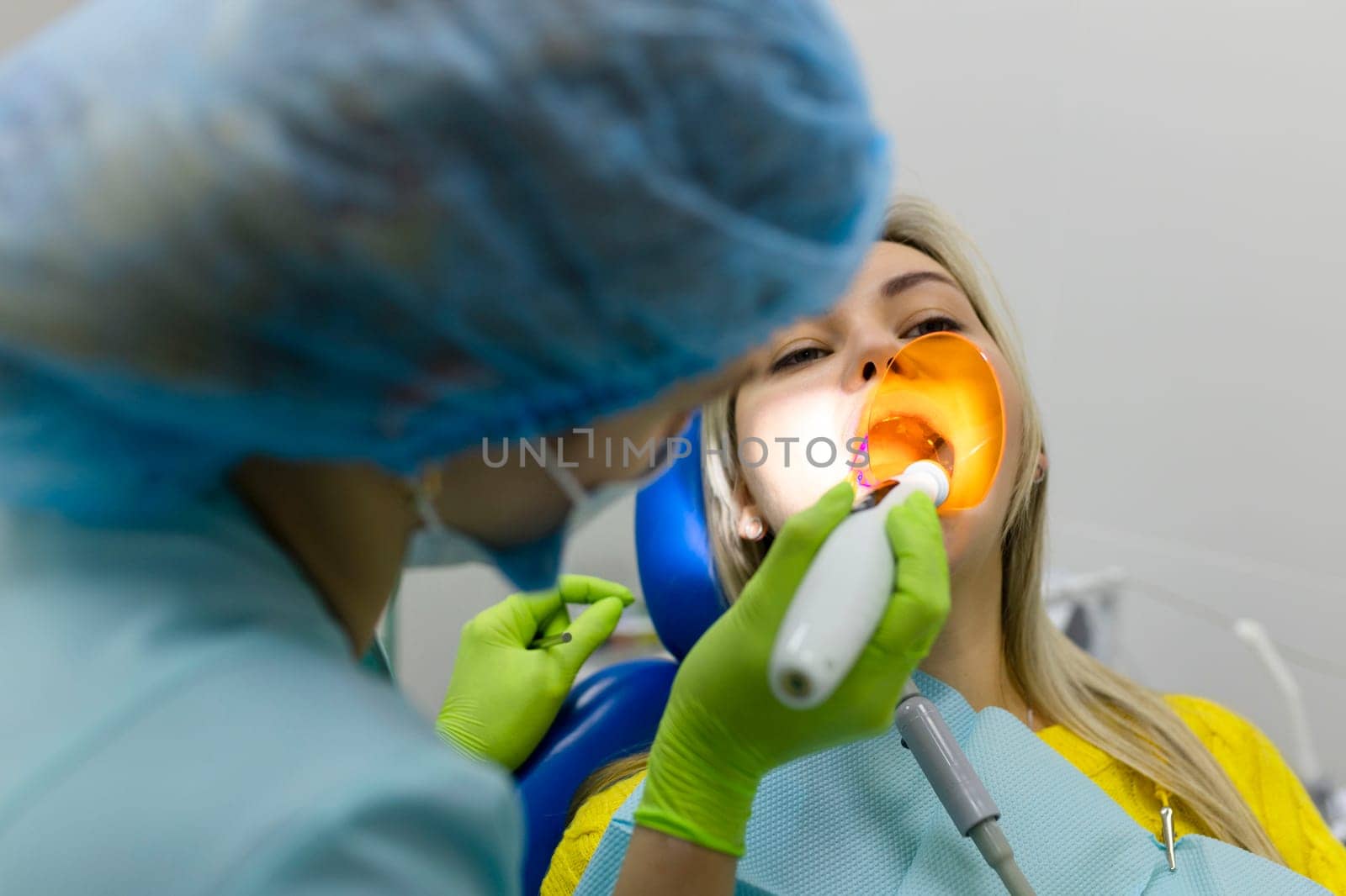 Medicine, dentistry and healthcare concept, dentist using dental curing UV lamp on teeth of patient