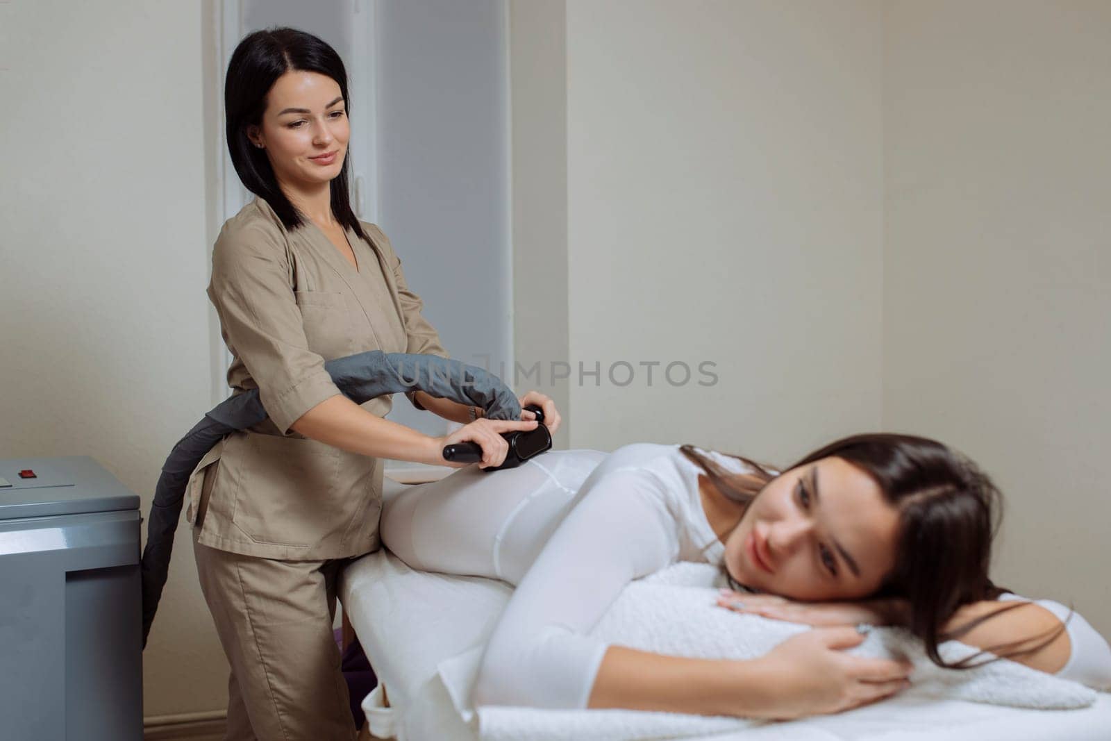 Woman in special white suit getting anti cellulite massage in a spa salon. LPG, and body contouring treatment in clinic.Reset body weight with LPG massage.