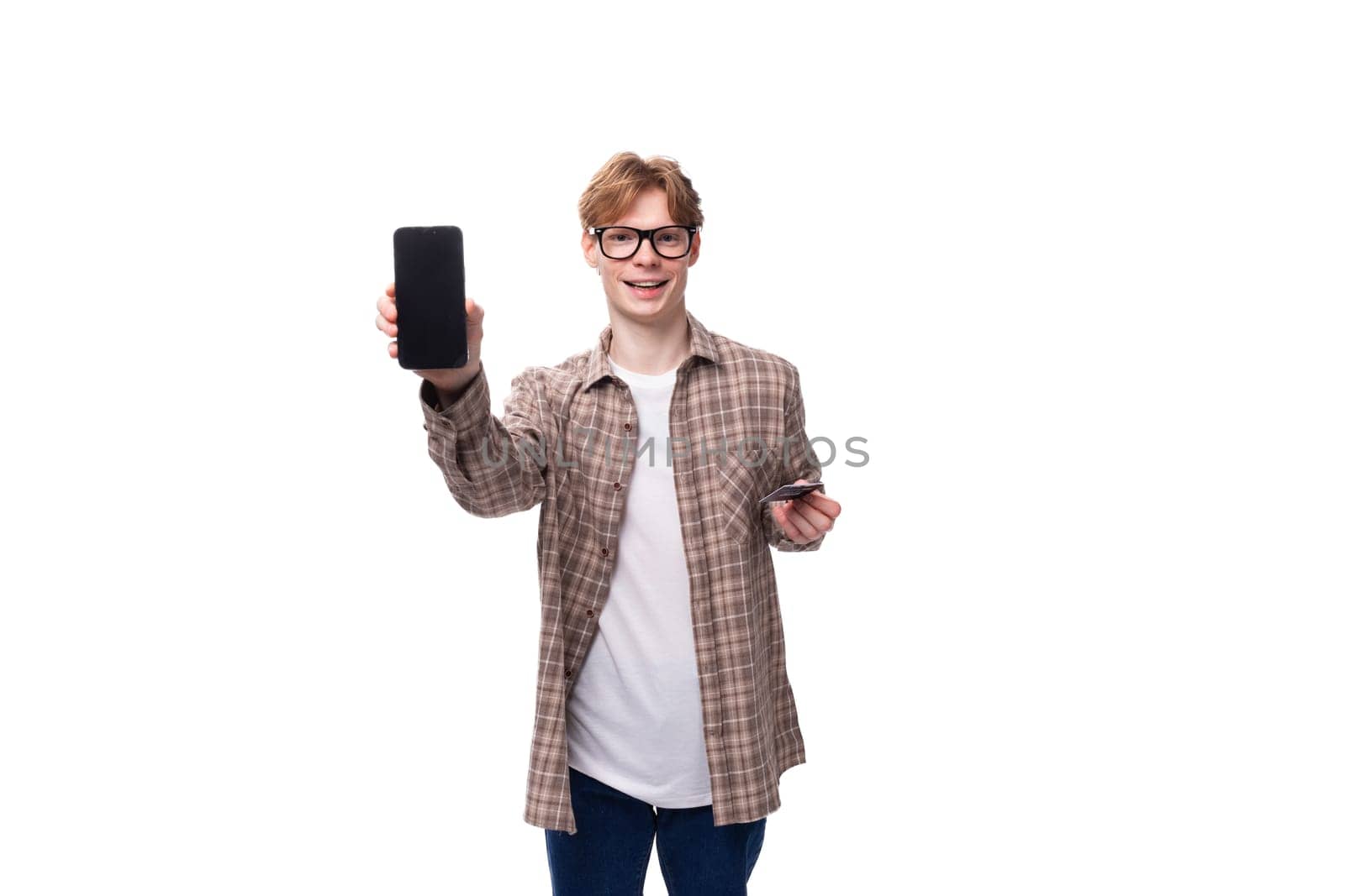 young handsome red-haired guy in a plaid shirt shows ads on the phone.