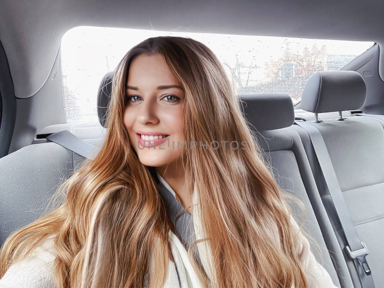 Young woman with long hair, wavy hairstyle in the car or taxi cab as passenger, exploring the city, transport and travel idea