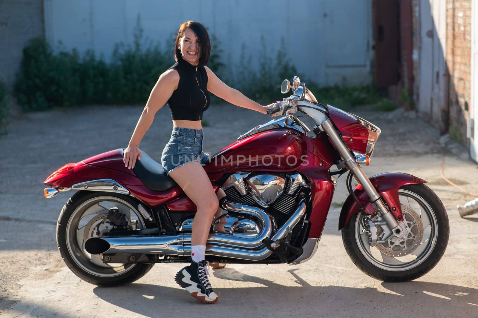 Brunette woman in shorts on a red motorcycle. by mrwed54