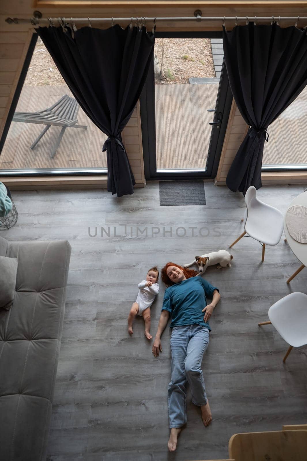 Top view of caucasian woman lying on floor with son and jack russell terrier dog. Vertical photo