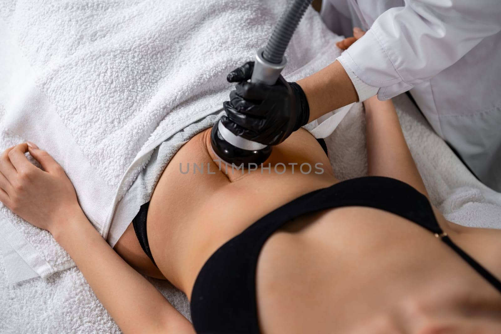 A cosmetologist utilizes an ultrasound device during a lifting procedure on a woman's abdomen