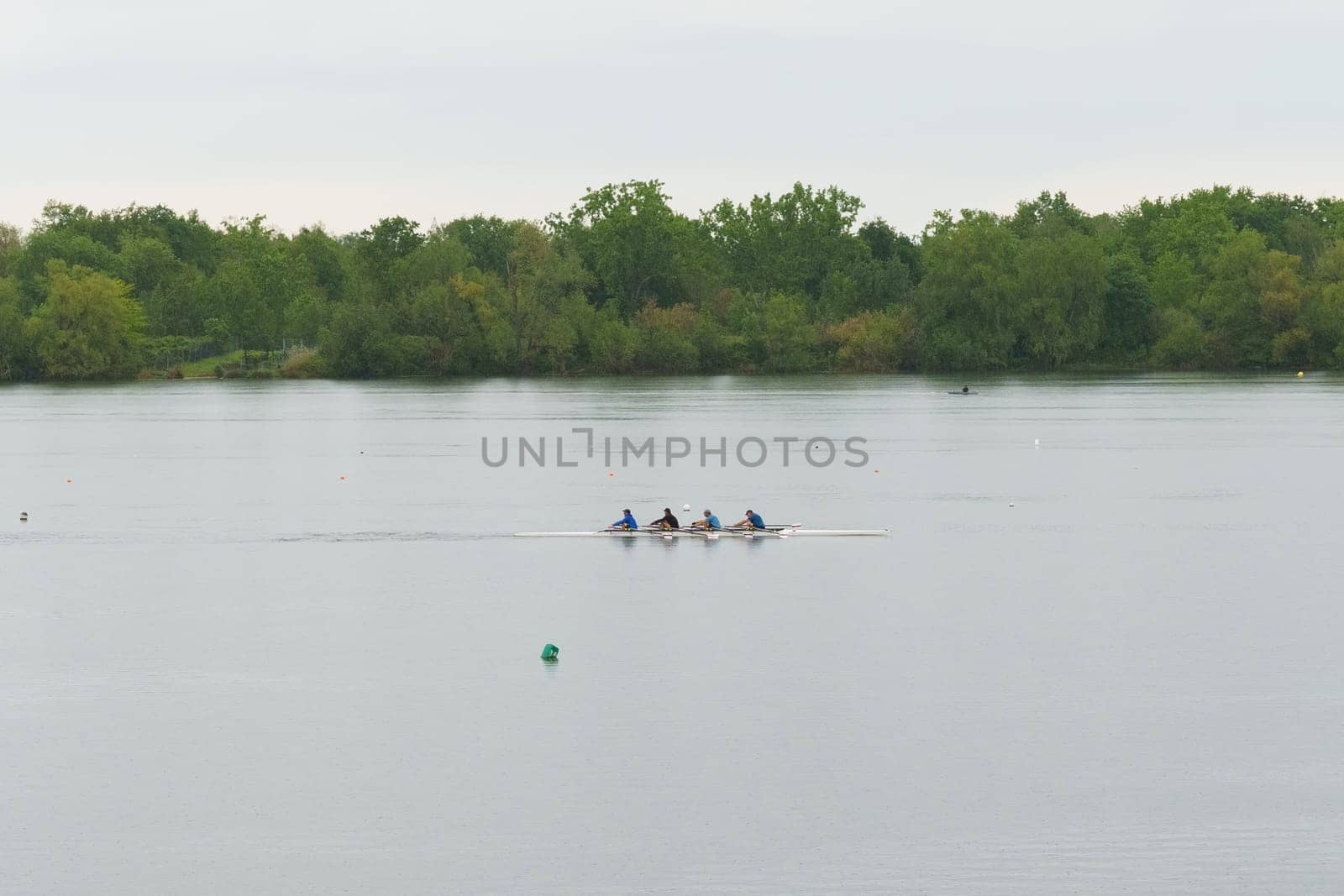 Bordeaux, France - April 26, 2023: A group of people rowing a boat on a serene lake, enjoying a day of outdoor adventure and teamwork.