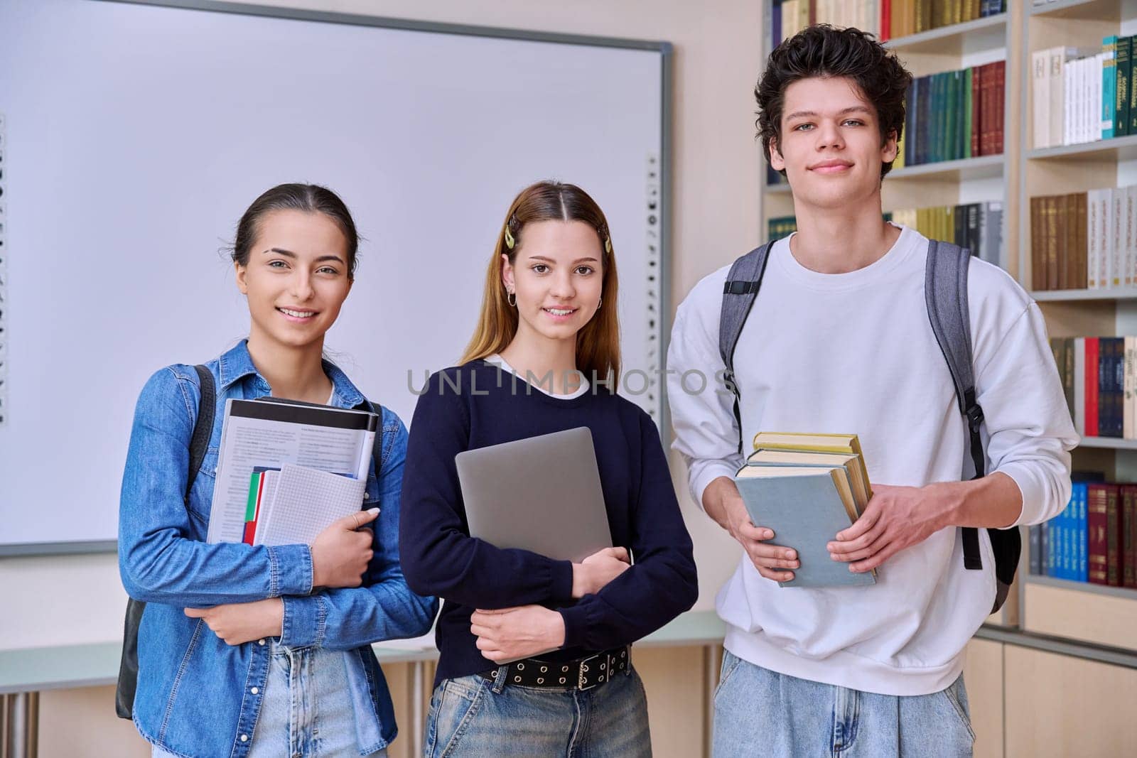 Portrait of group of teenage students in library classroom by VH-studio