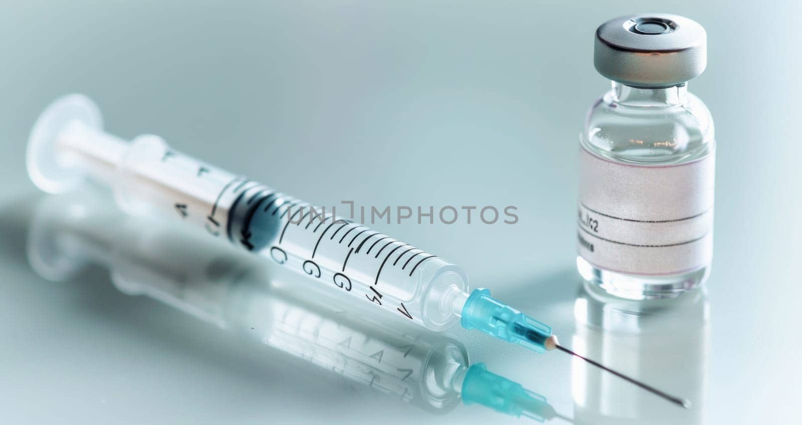 Beside the bottle on the table sits a syringe filled with vaccine, essential for the organisms health