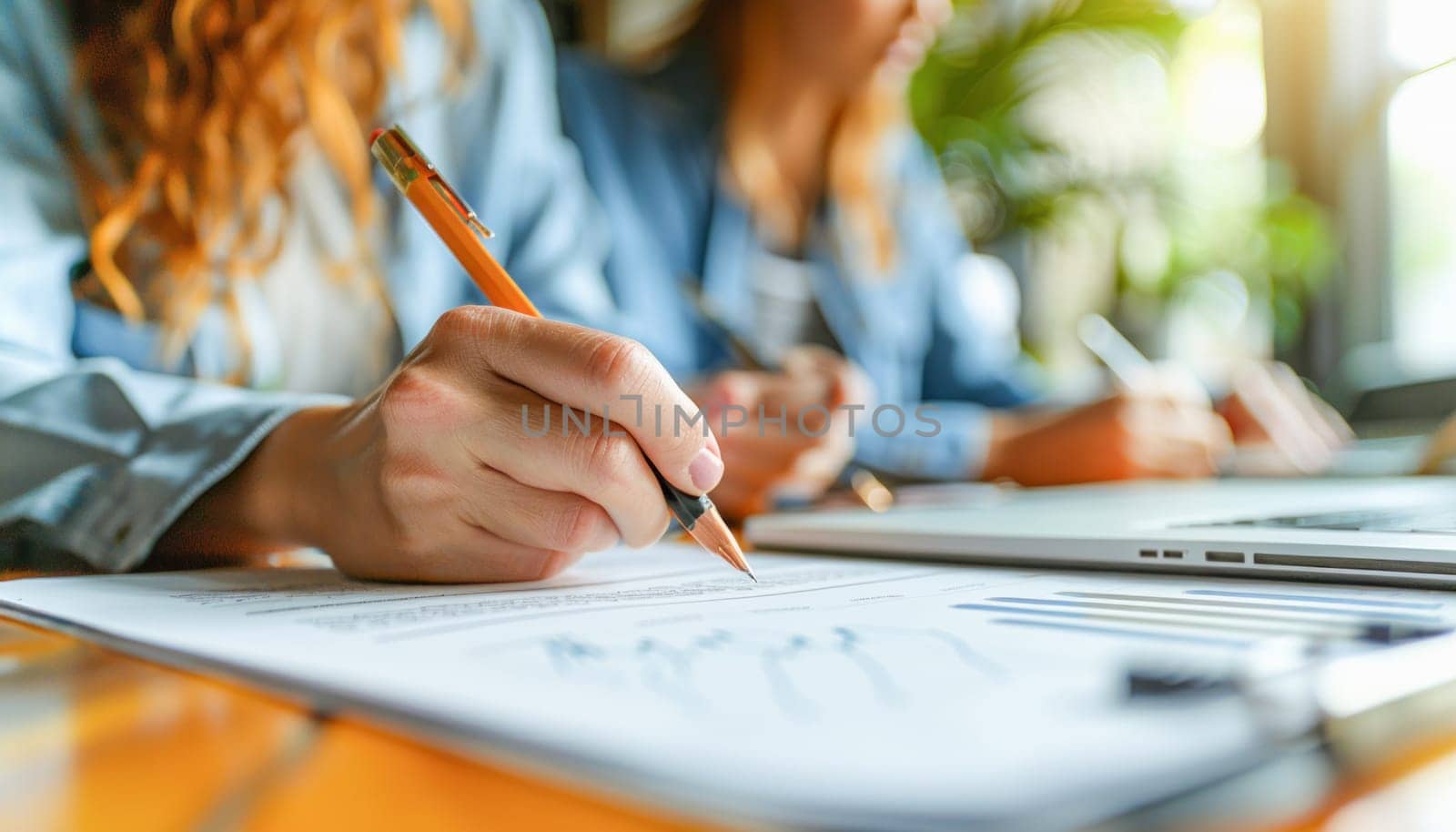 A woman is focused while holding a pencil and writing on a piece of paper, emphasizing the act of handwriting