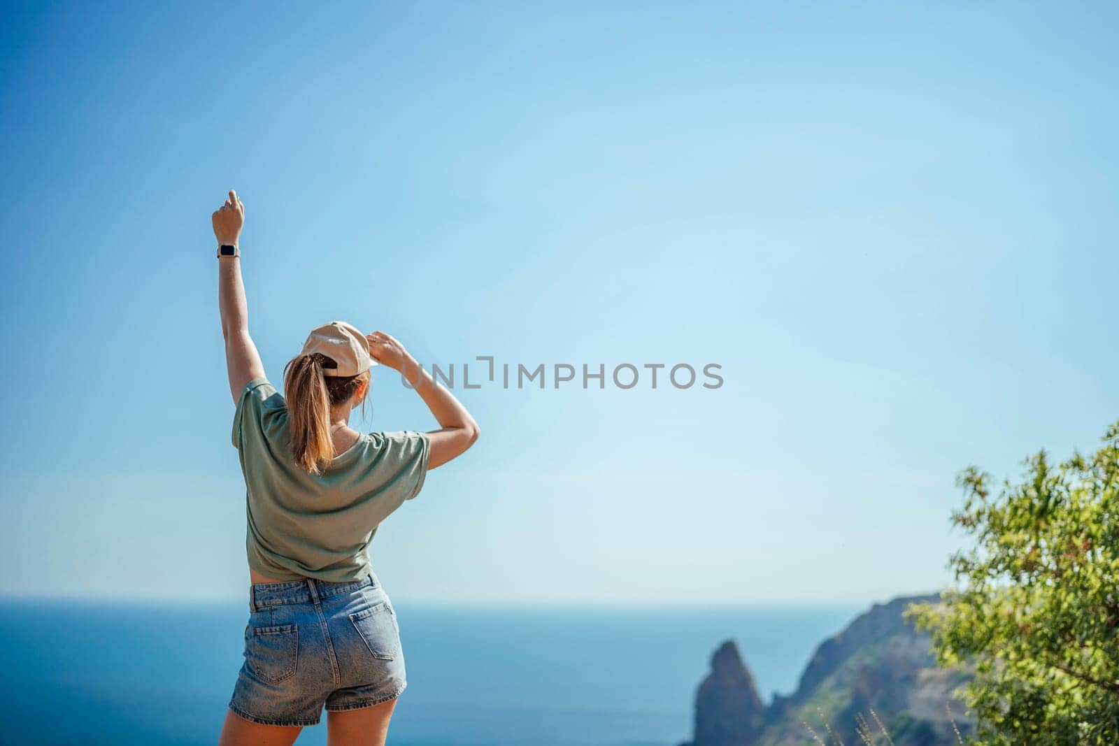 Woman tourist sky sea. Happy traveler woman in hat enjoys vacation raised her hands up.