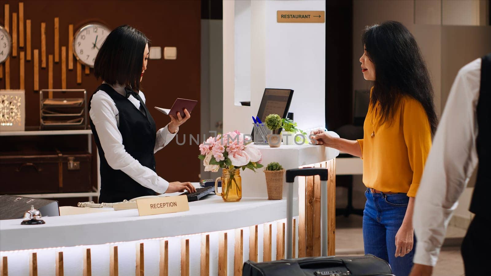 Asian hotel staff checking passport for id at check in by DCStudio