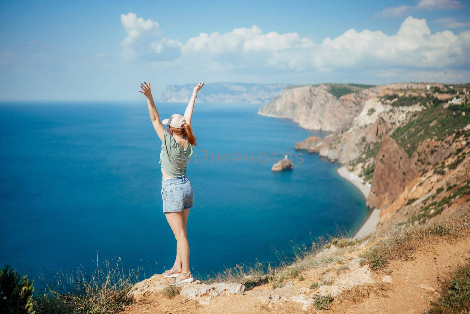 Woman tourist sky sea. Happy traveler woman in hat enjoys vacation raised her hands up by Matiunina