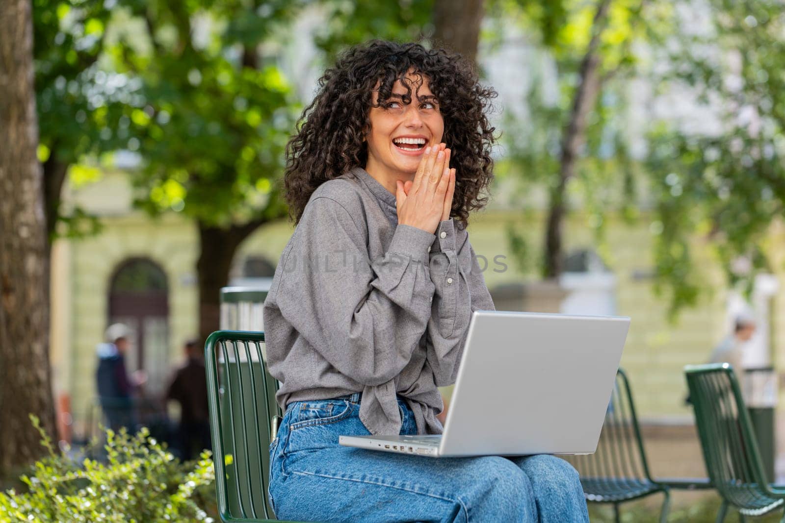 Happy Caucasian young woman working on laptop screams in triumph win celebrating good message news success game casino lottery money jackpot victory outdoor. Lady girl on urban city street. Sunny park