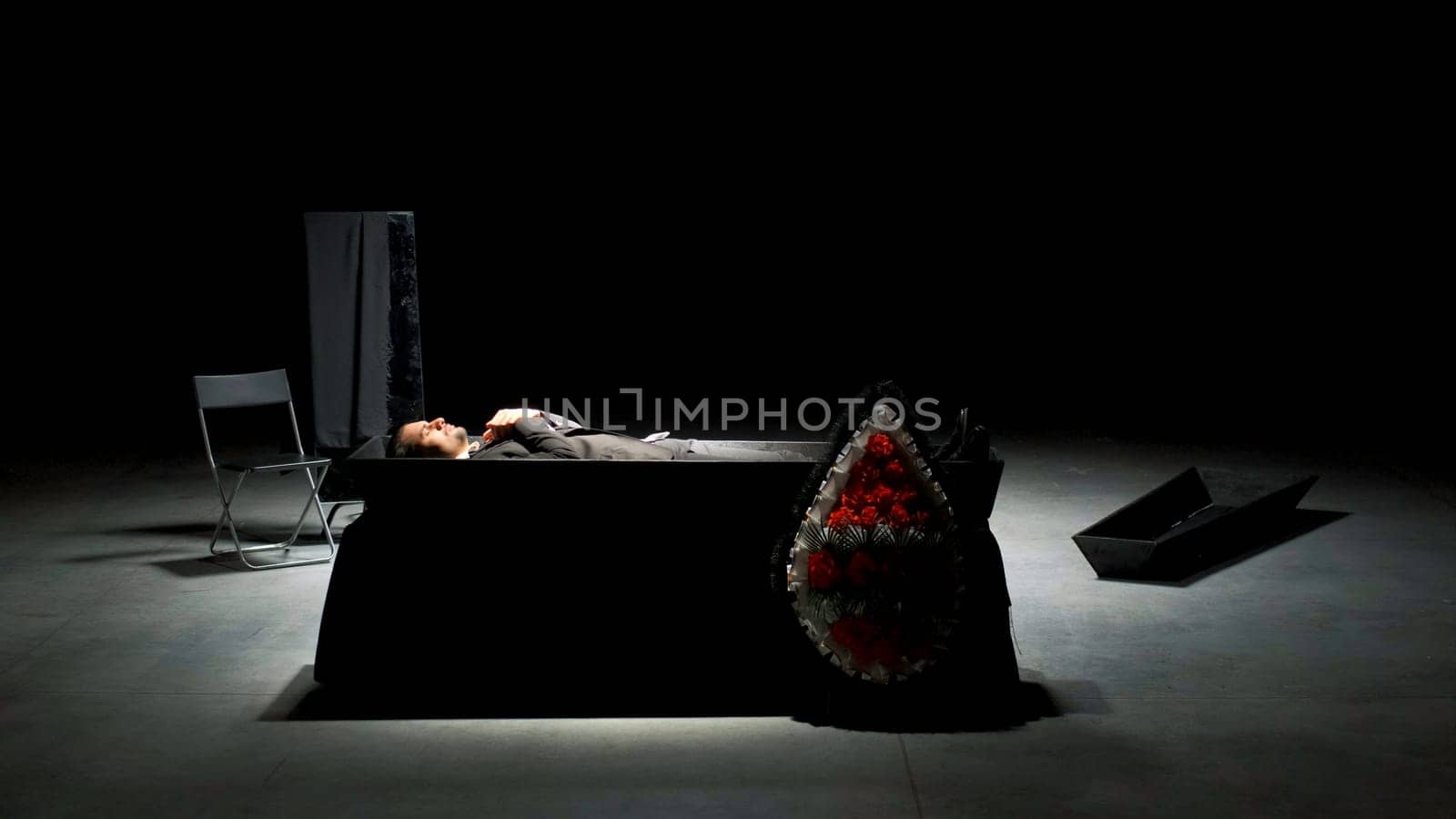 Theatrical funeral. Stock footage. Man in suit is buried on theater stage. Emotional stage production of funeral.