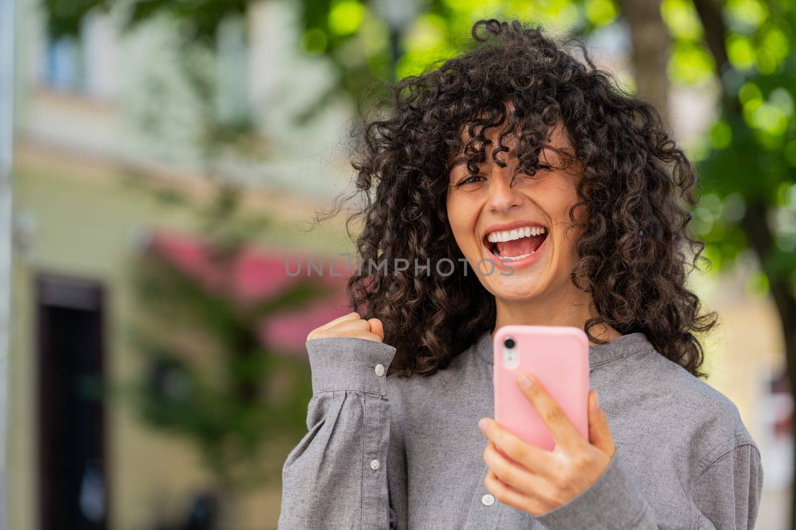 Caucasian young woman use mobile smartphone celebrating win good message news, lottery casino jackpot victory, giveaway online outdoors. Lady girl on urban city street. Town lifestyles. Sunny park