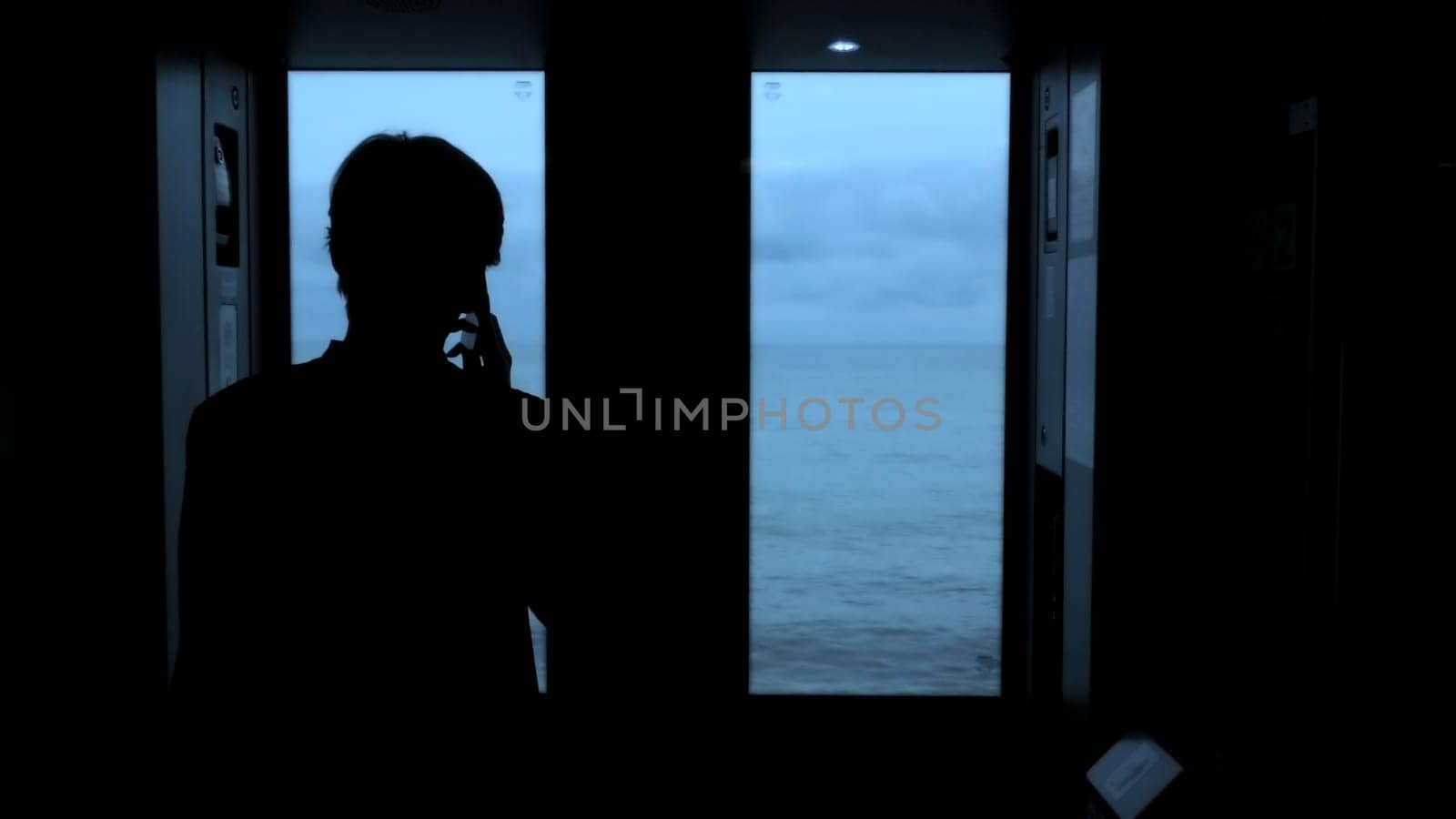 Young man standing next to a train window and looking outside Stock clip. Man with smartphone looking through the window on sea. by Mediawhalestock