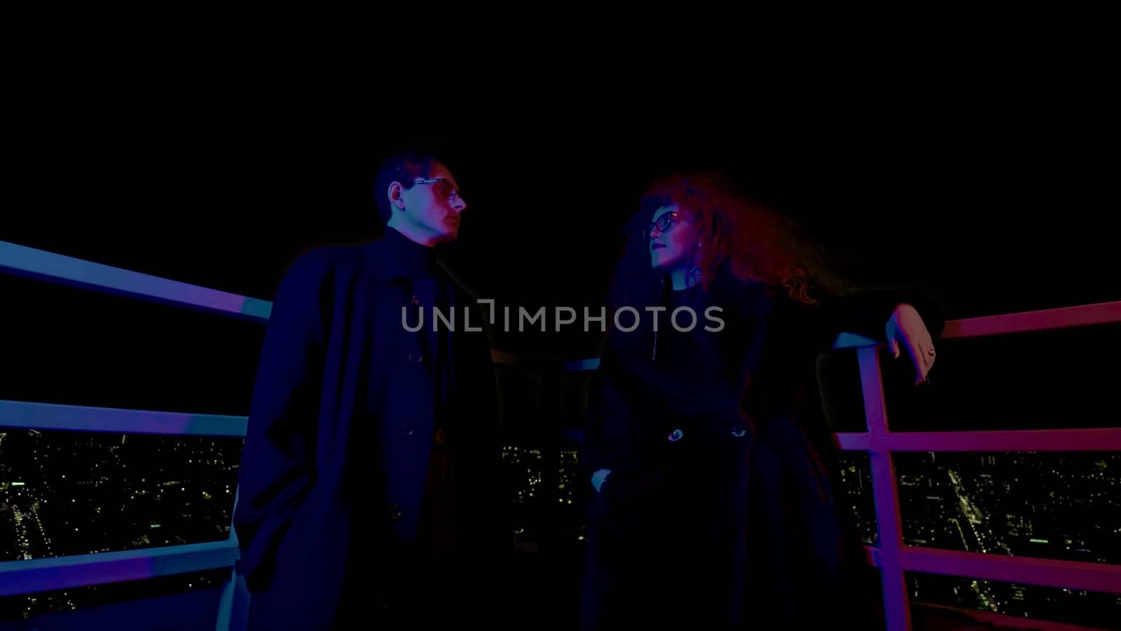 Man and woman on roof at night. Media. Couple of night heroes on roof of high-rise. Man and woman with glasses look like super villains by Mediawhalestock