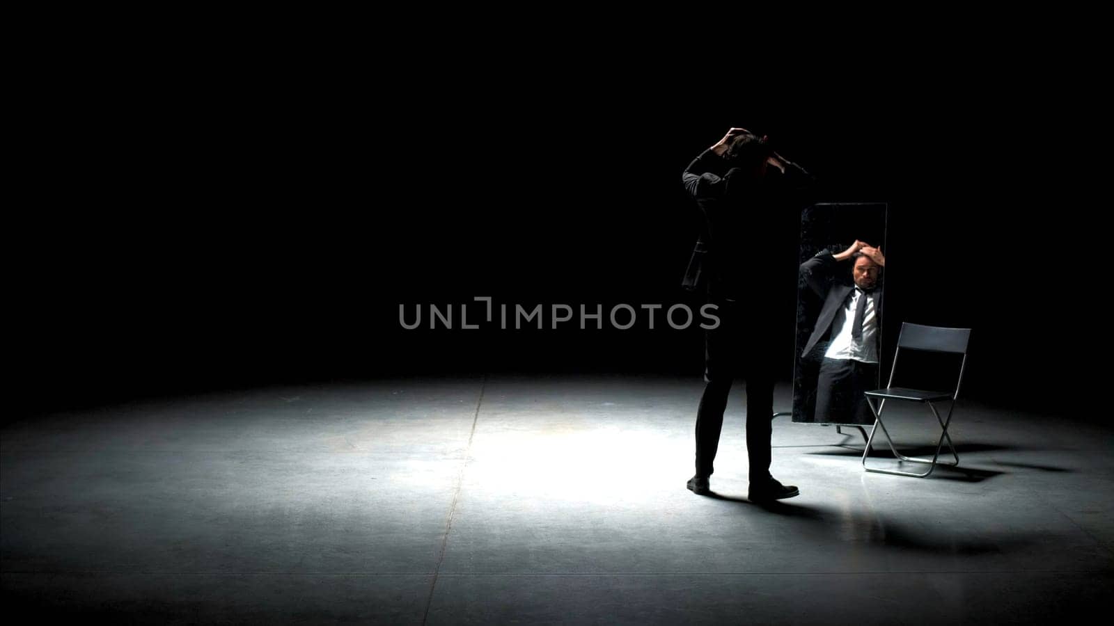 Man in suit combs his hair. Stock footage. Handsome man combs his hair in front of mirror. Man in suit combs his hair on theater stage.