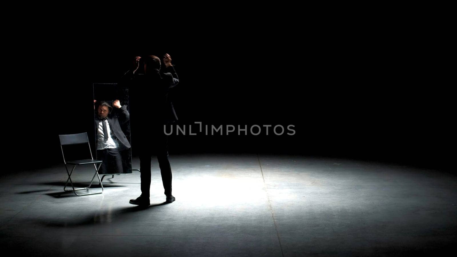 Man in suit combs his hair. Stock footage. Handsome man combs his hair in front of mirror. Man in suit combs his hair on theater stage.