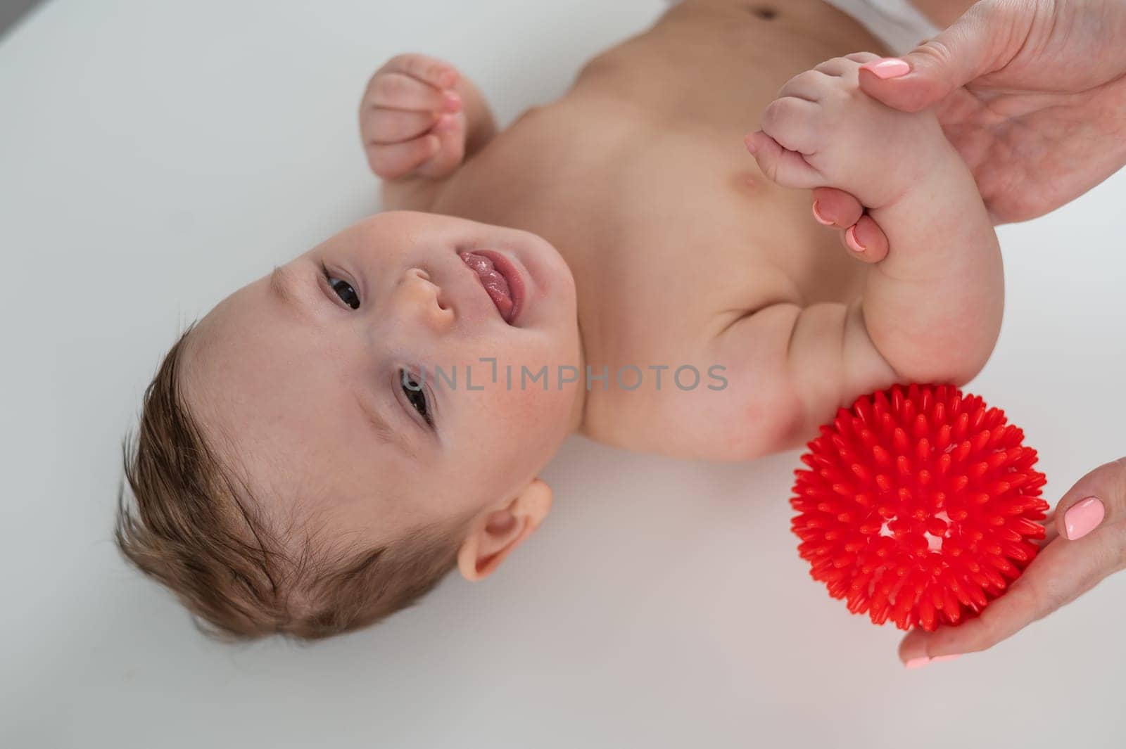 A doctor gives a baby a shoulder massage using a ball. by mrwed54