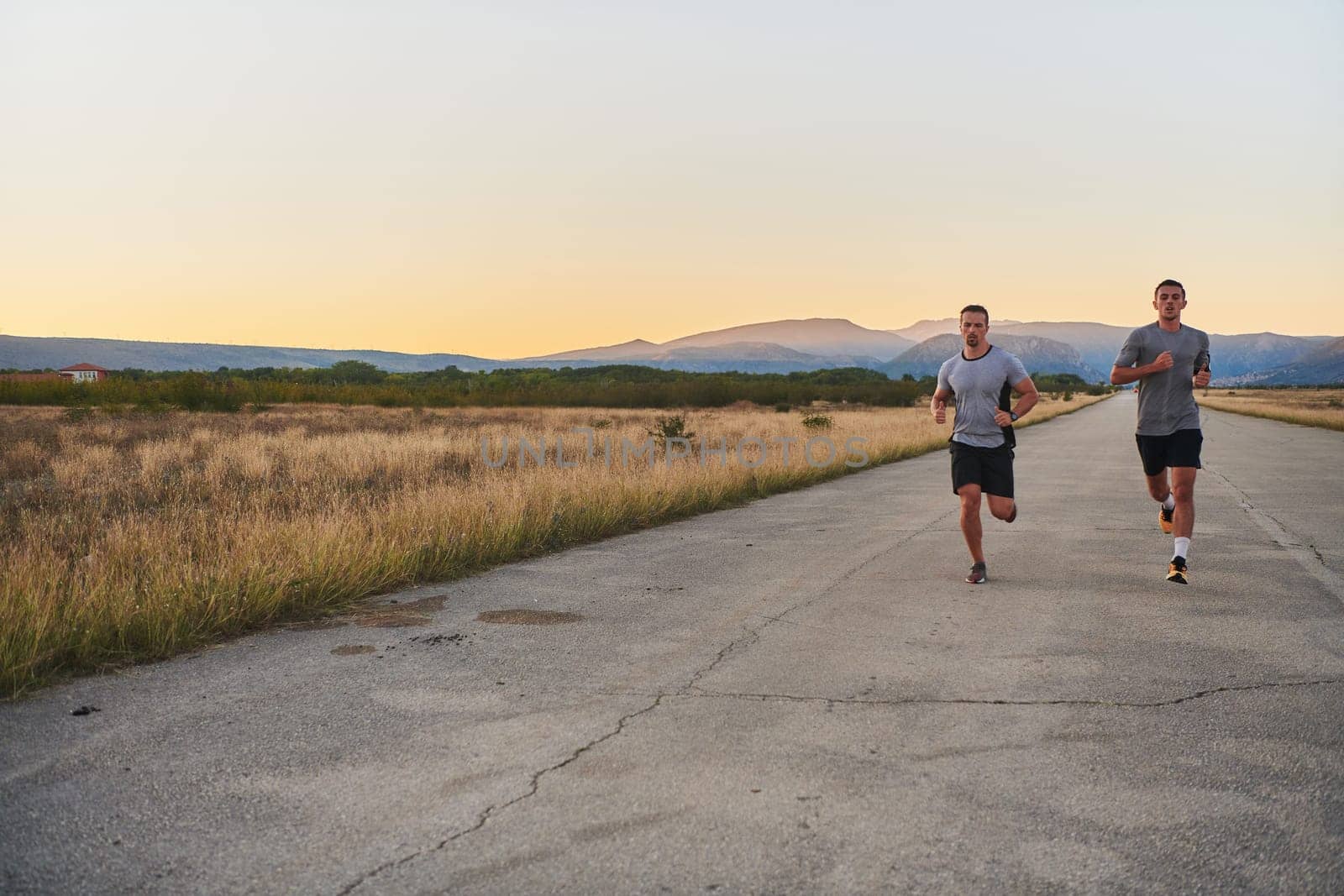 Group of handsome men running together in the early morning glow of the sunrise, embodying the essence of fitness, vitality, and the invigorating joy of embracing nature's tranquility during their refreshing and energizing workout