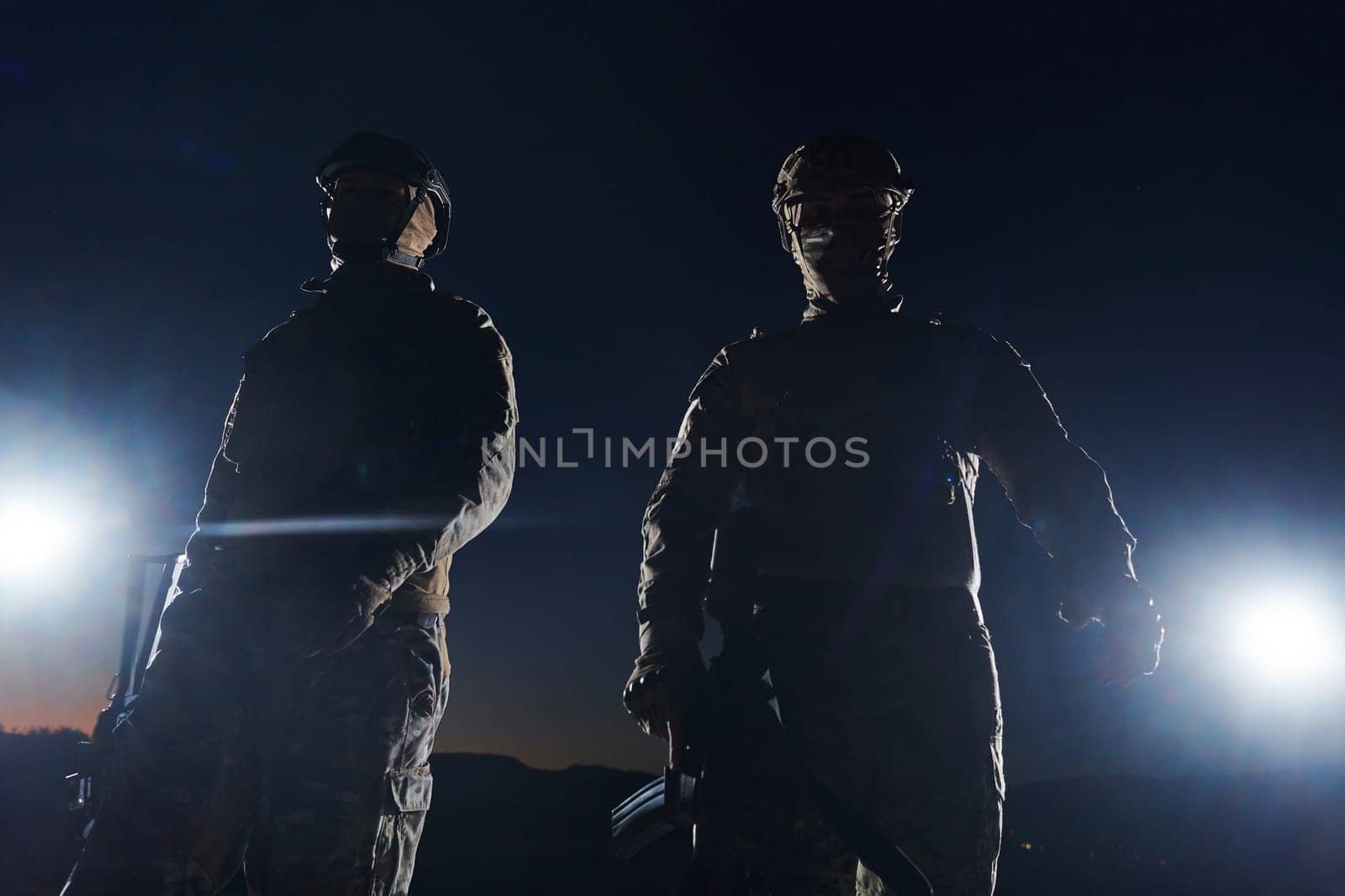 Two professional soldiers marching through the dark of night on a dangerous mission, epitomizing their unwavering bravery, unwavering teamwork, and the high-stakes intensity of their specialized training as they prepare to confront unknown perils in the name of duty and sacrifice