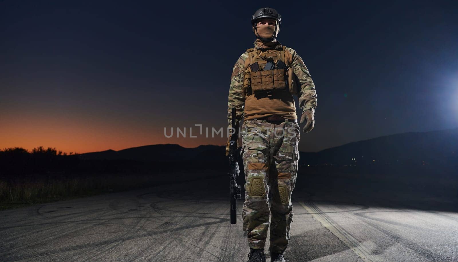 A professional soldier in full military gear striding through the dark night as he embarks on a perilous military mission.