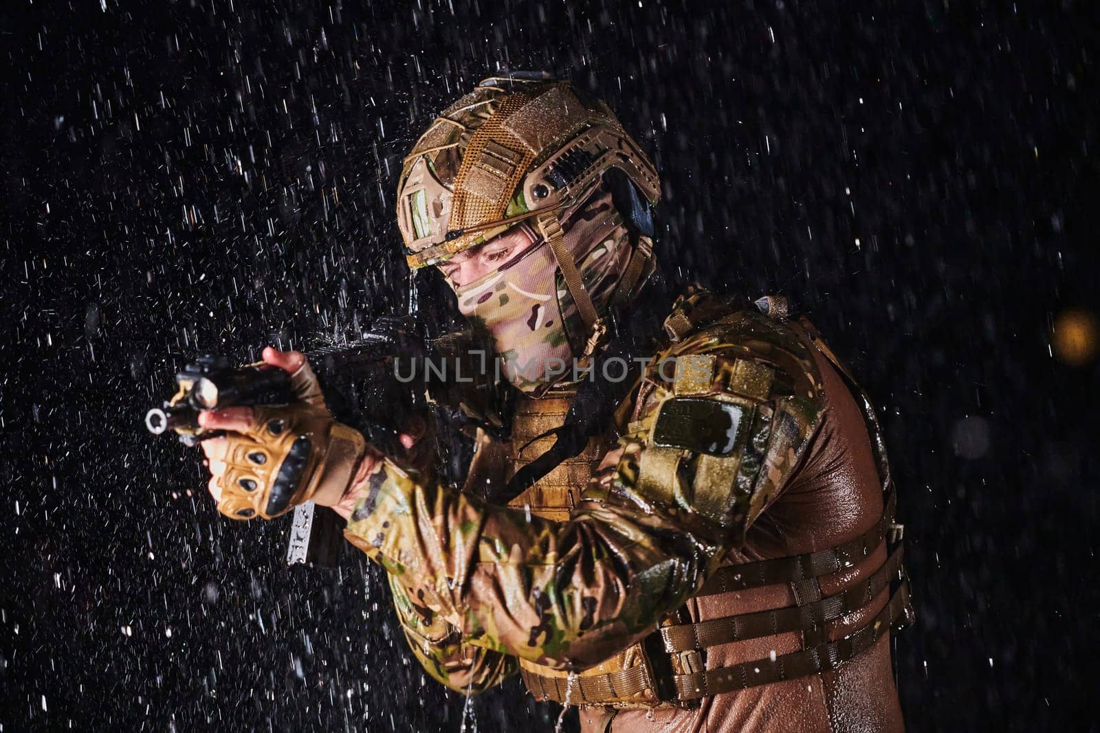 Army soldier in Combat Uniforms with an assault rifle, plate carrier and combat helmet going on a dangerous mission on a rainy night. by dotshock