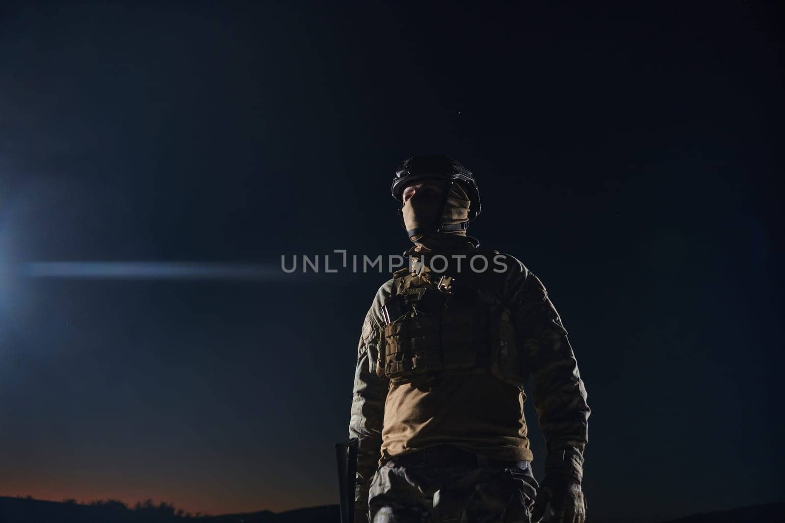 A professional soldier in full military gear striding through the dark night as he embarks on a perilous military mission.