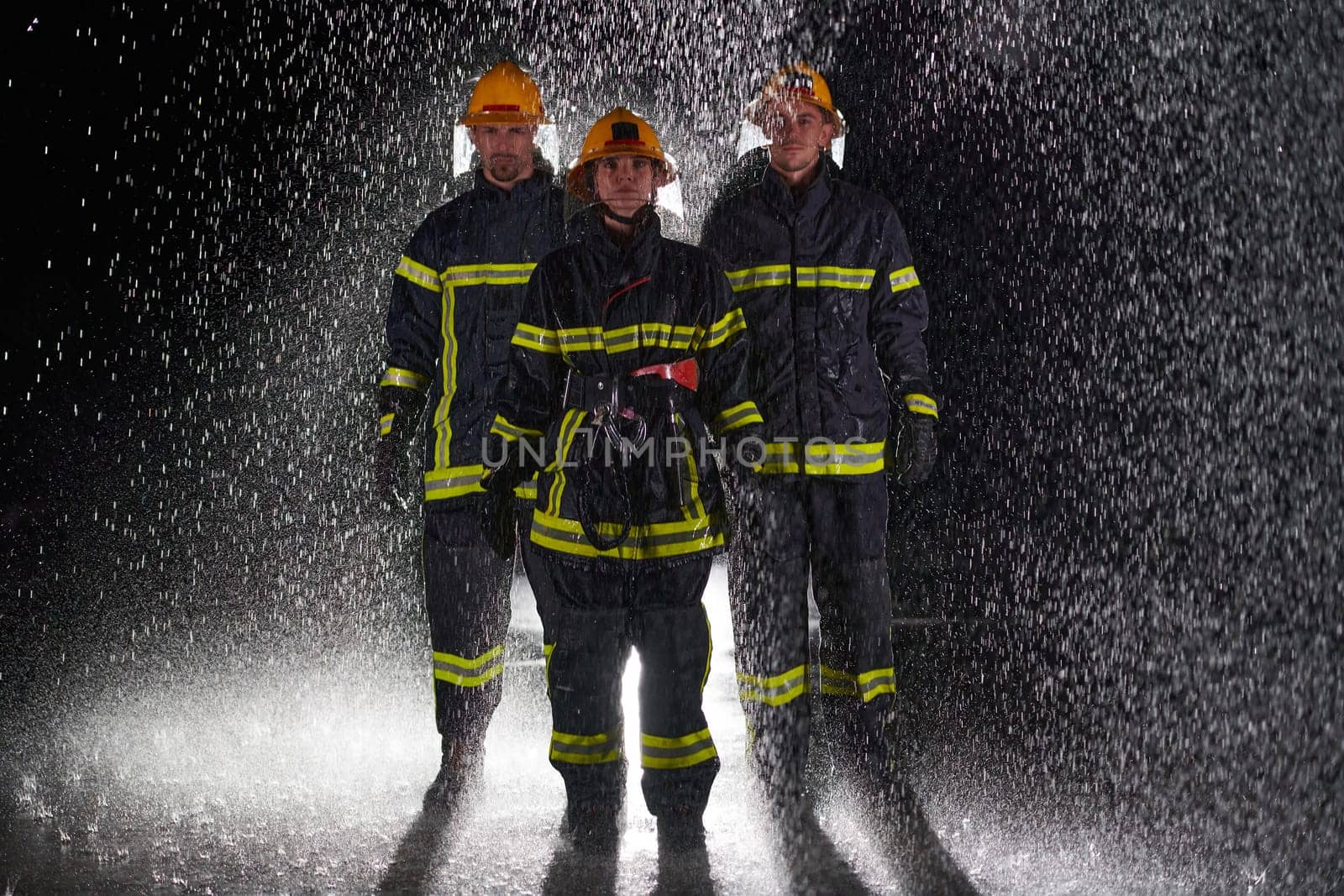 A group of professional firefighters marching through the rainy night on a rescue mission, their determined strides and fearless expressions reflecting their unwavering bravery and unwavering commitment to saving lives