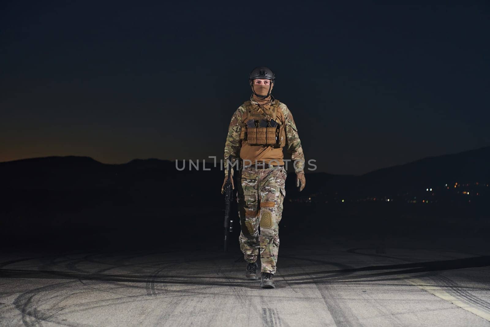 A professional soldier in full military gear striding through the dark night as he embarks on a perilous military mission.