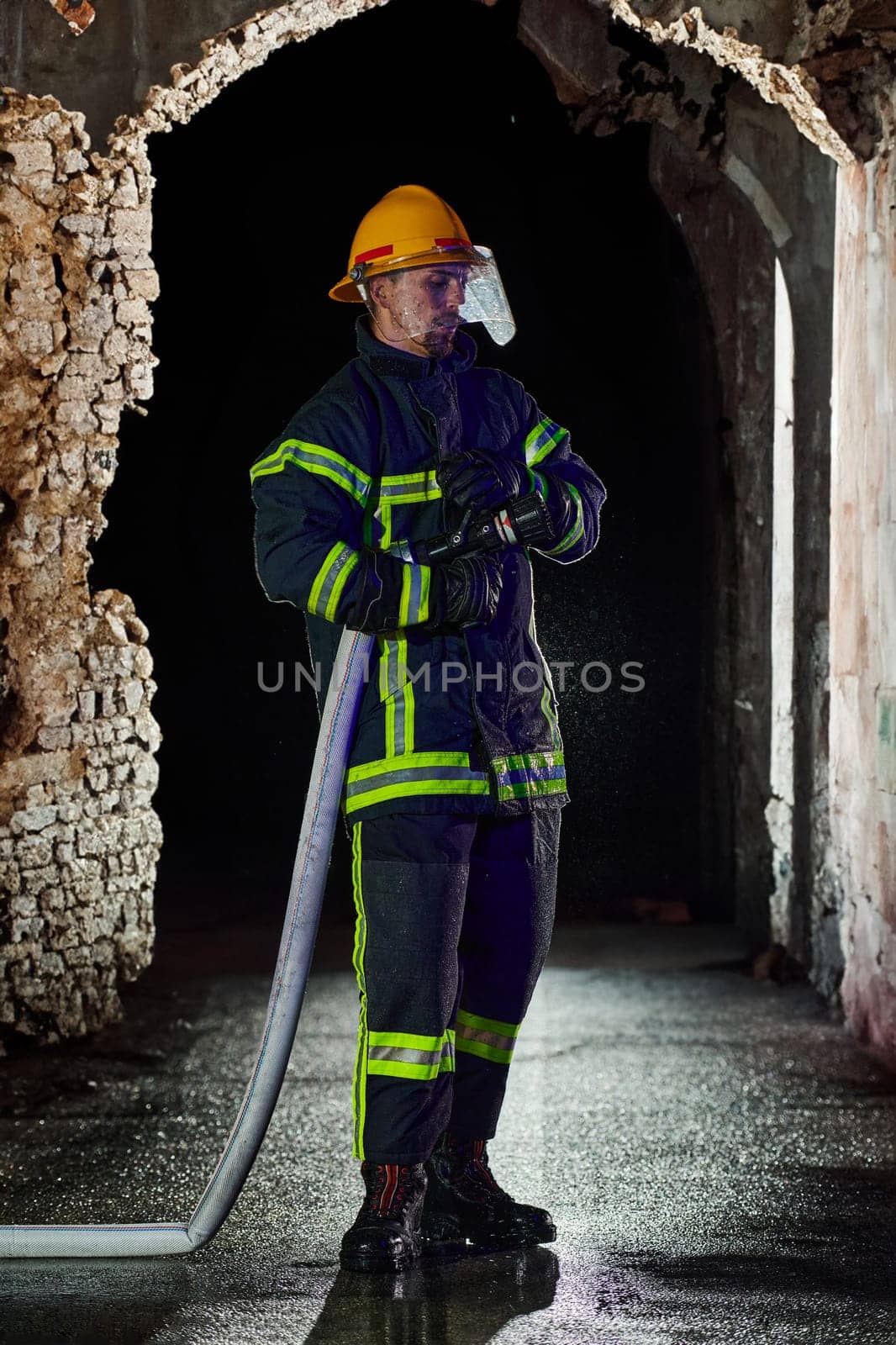 Firefighter using a water hose to eliminate a fire hazard. Team of female and male firemen in dangerous rescue mission