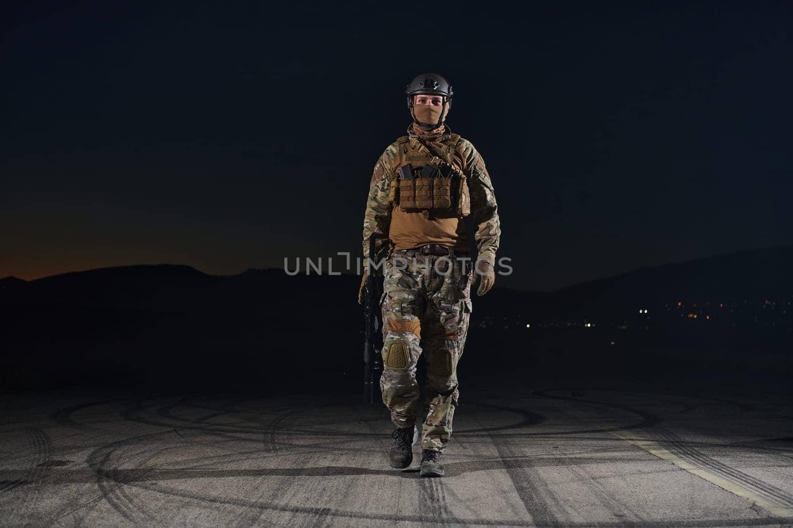 A professional soldier in full military gear striding through the dark night as he embarks on a perilous military mission.