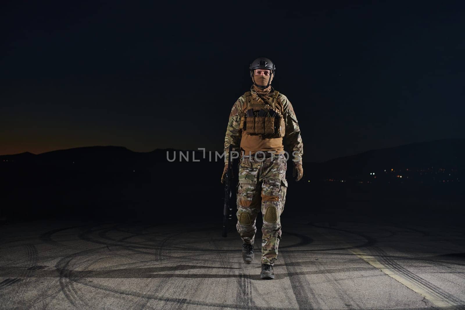 A professional soldier in full military gear striding through the dark night as he embarks on a perilous military mission.