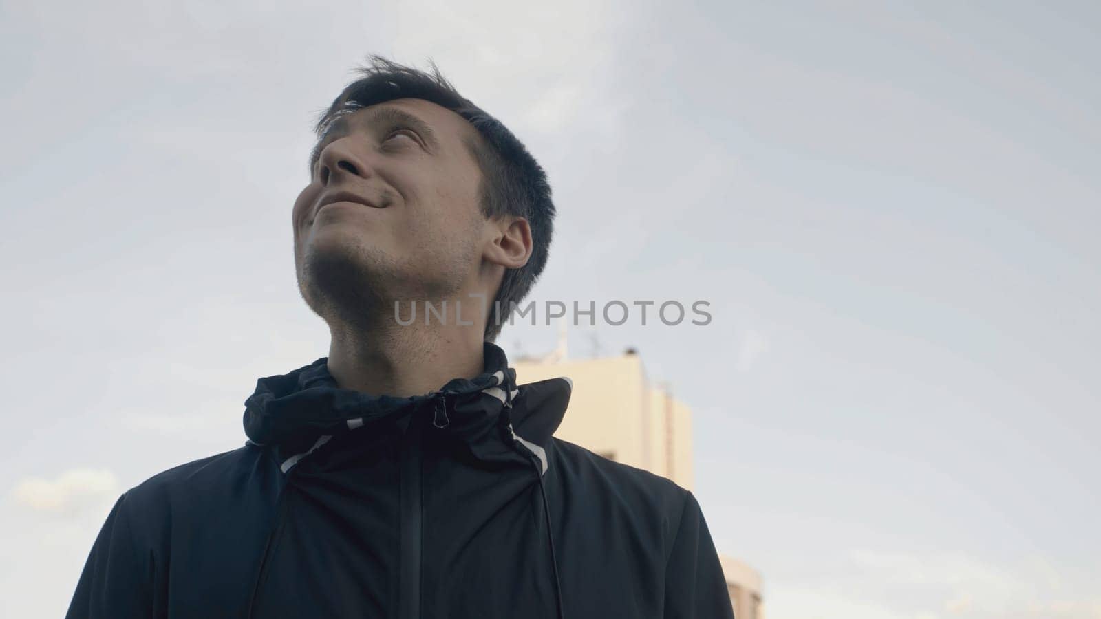 Close-up of man looking at sky with smile. Stock. Man looks up happily and inspiringly. Man looks back up and smiles happily.