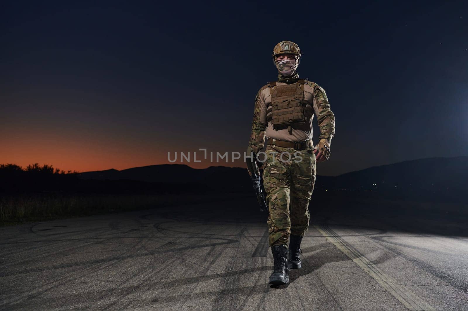 A professional soldier in full military gear striding through the dark night as he embarks on a perilous military mission.