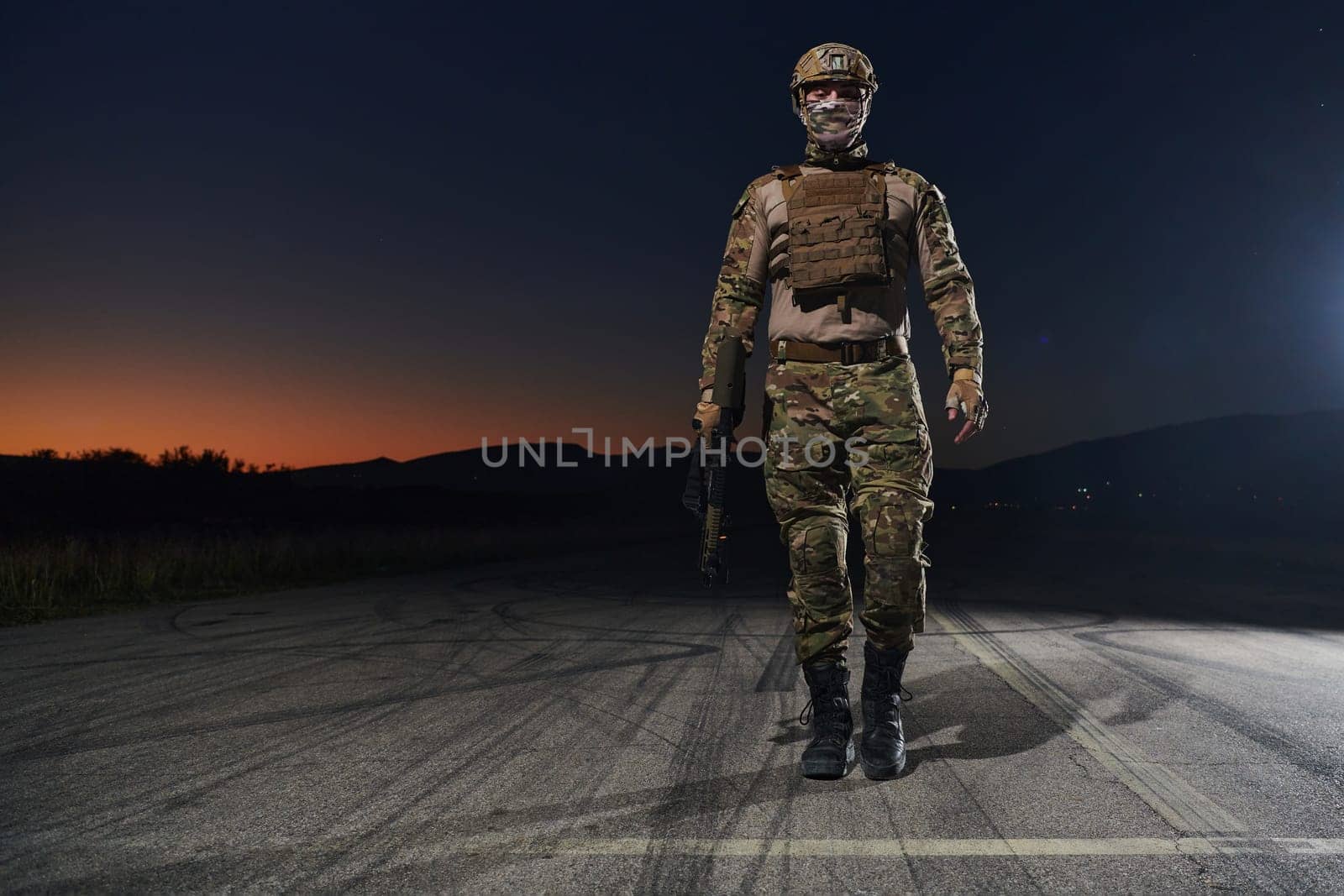 A professional soldier in full military gear striding through the dark night as he embarks on a perilous military mission.