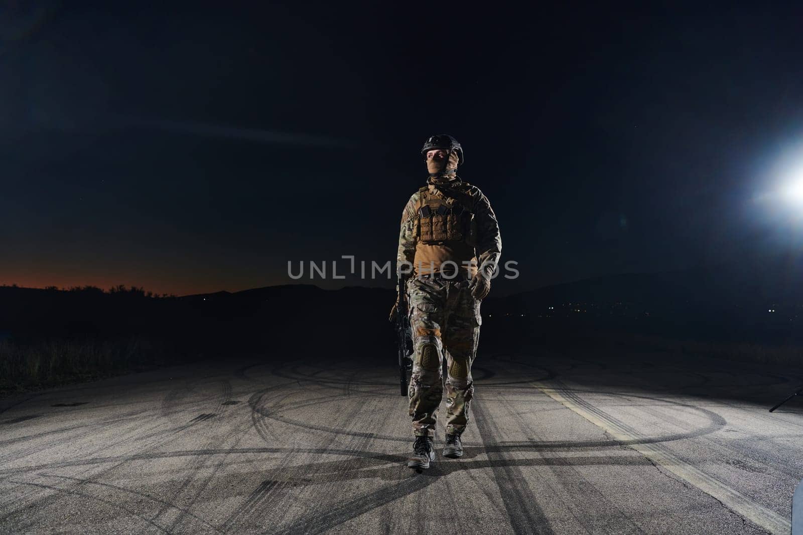 A professional soldier in full military gear striding through the dark night as he embarks on a perilous military mission by dotshock