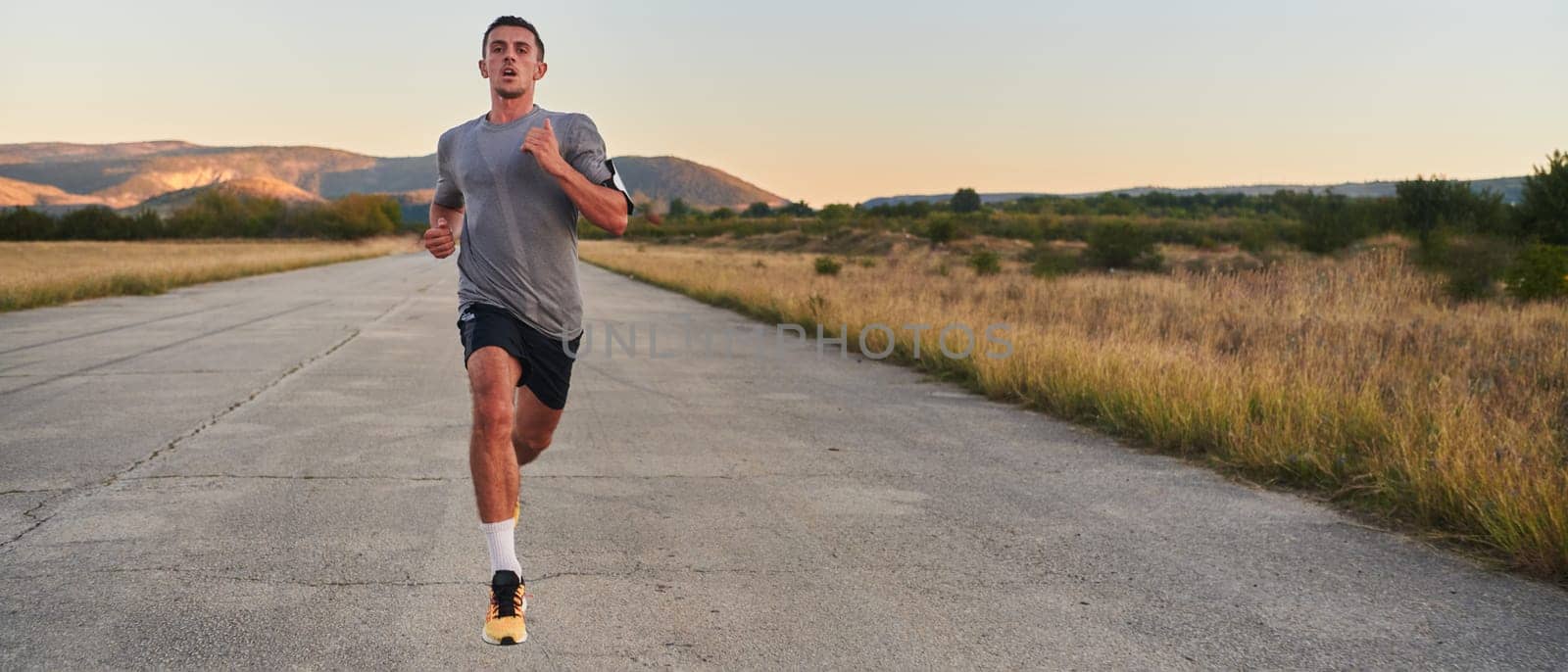 A young handsome man running in the early morning hours, driven by his commitment to health and fitness by dotshock