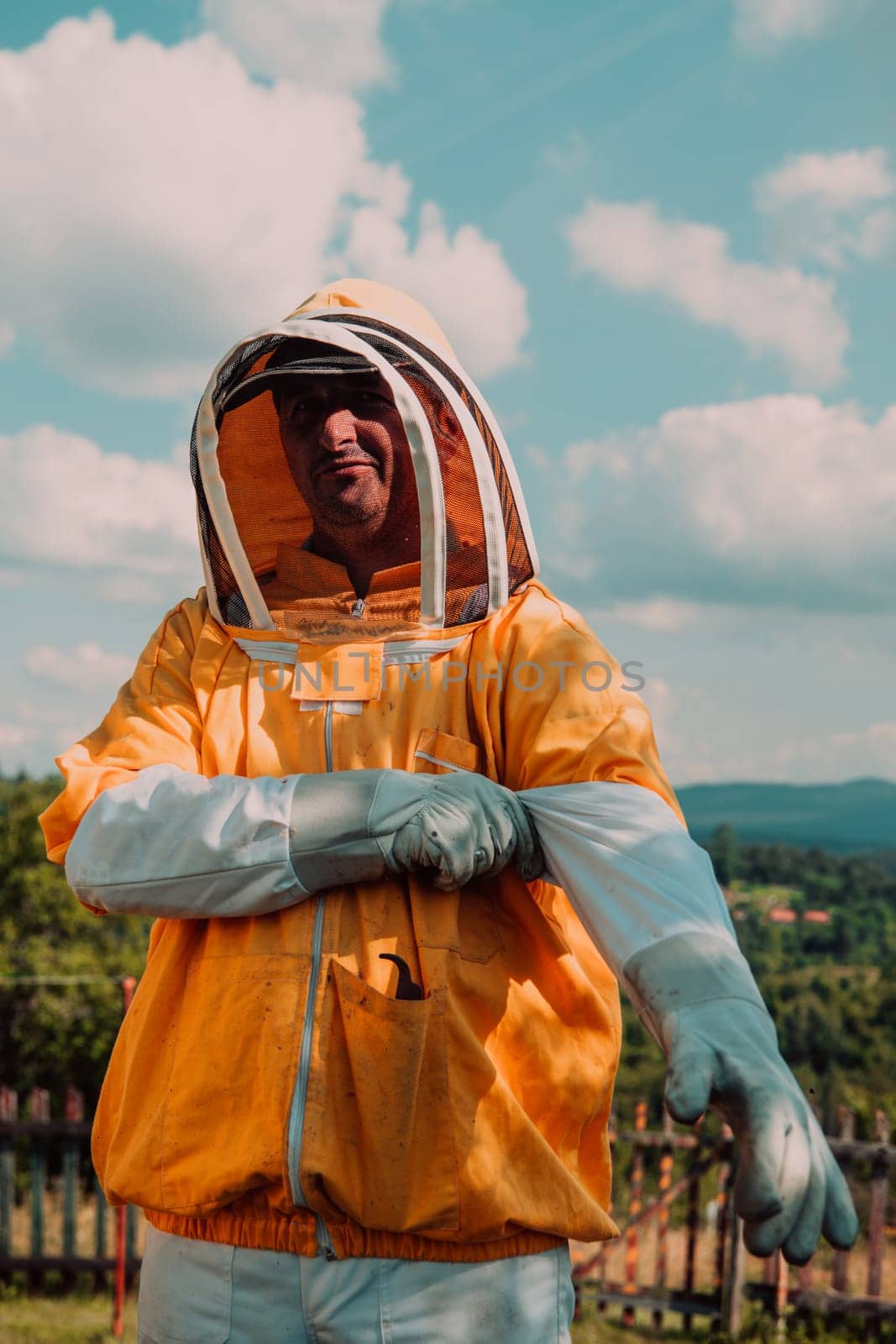 Beekeeper put on a protective beekeeping suit and preparing to enter the apiary.